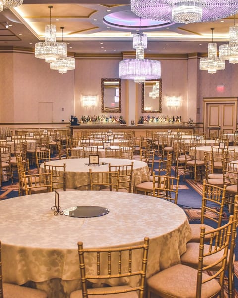 A bright celebration venue with beautifully set round tables and hanging lights
